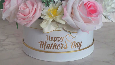 This stunning foam rose arrangement, made with lifelike fabric and soft foam pink and white roses, is a true embodiment of elegance. The beautiful assortment of pink and white flowers, carefully arranged in a white hat box with gold trimming, is sure to brighten up anyone's day. With the heartfelt "Happy Mother's Day" message and the lovely bow, it makes for a perfect gift to show your love and appreciation to your mother. to show your love and appreciation to your mother.